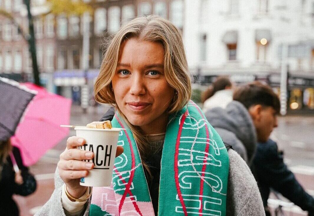 Persoon geniet van een warme STACH-koffie tijdens een regenachtige dag in Amsterdam