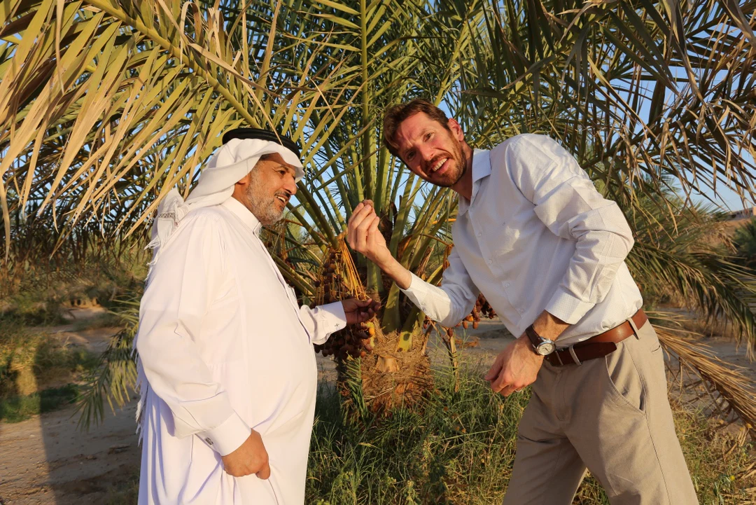Yogi & Yousef bekijken verse dadels aan een dadelpalm tijdens een bezoek aan een dadelplantage.